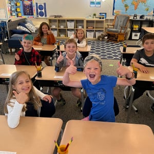 kids in classroom with thumbs up