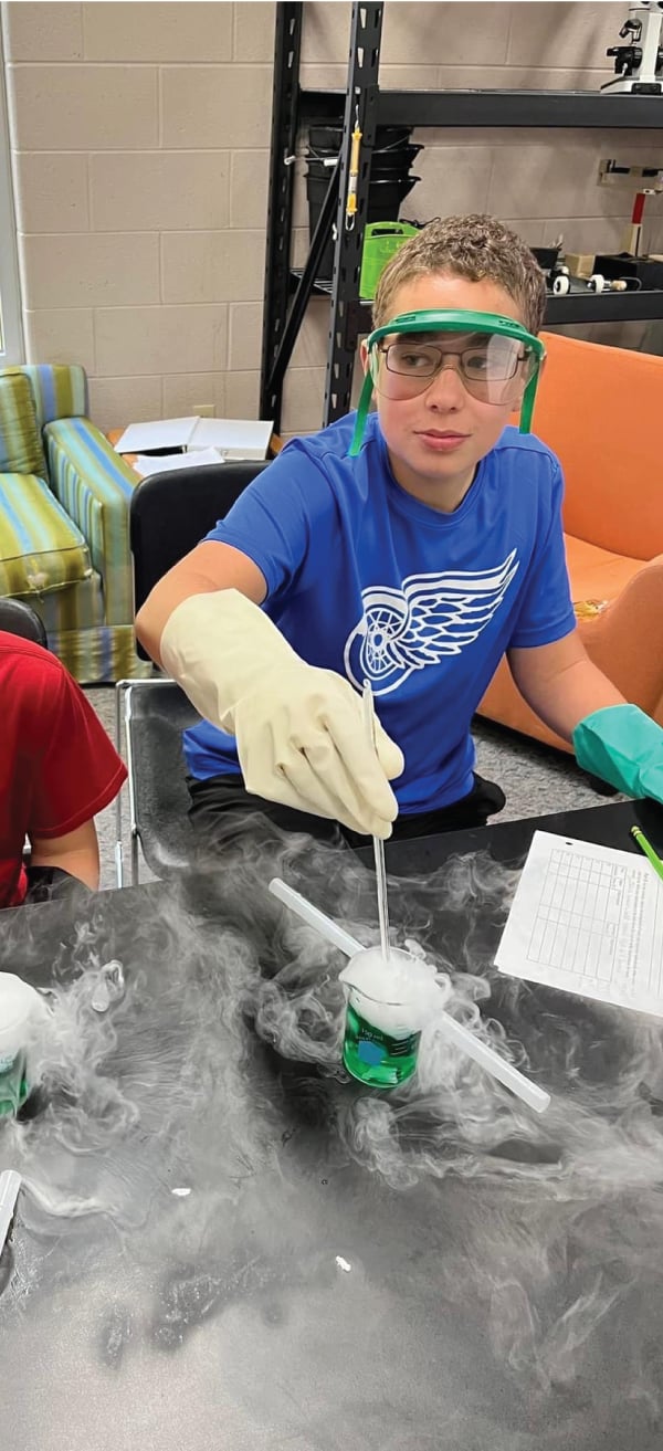 student doing science project with goggles and gloves on
