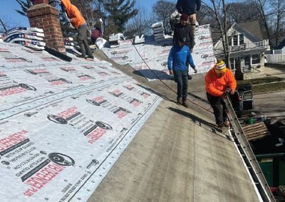 workers on top of house laying new shingles